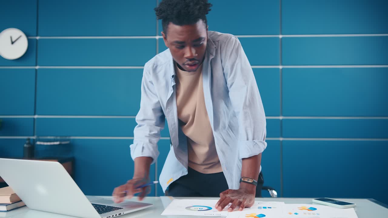 African american man stands at office desk taking notes planning agenda