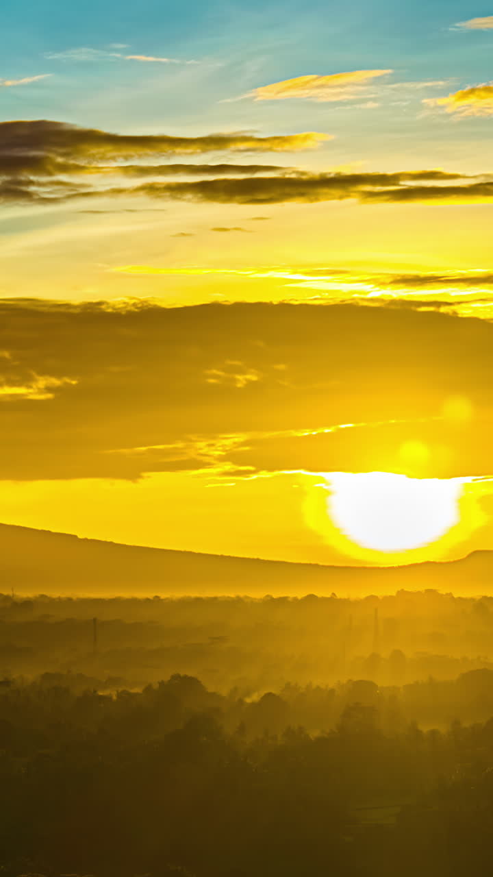 Golden sunrise timelapse over misty Bali landscape with trees and glowing sky, vertical