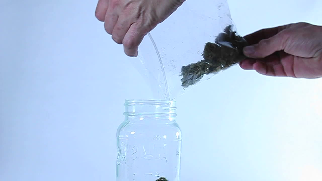 A man puts grass in a jar