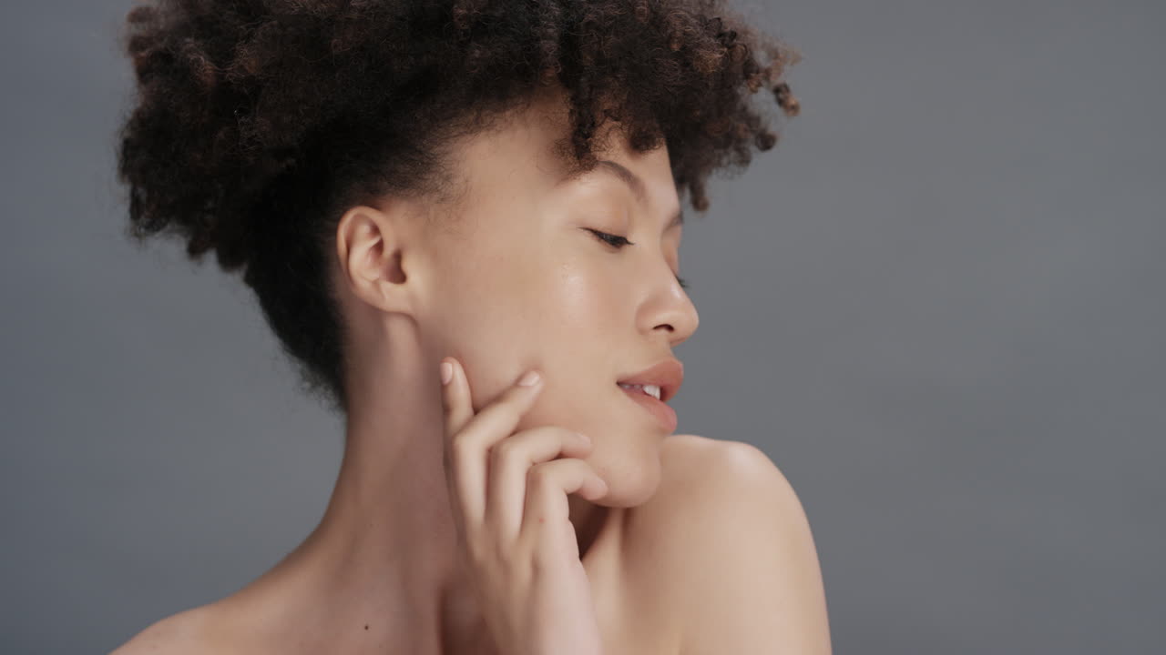 retrato de belleza de cerca mujer joven atractiva tocando el rostro con la mano acariciando una piel sana y perfecta disfrutando del cuidado natural de la piel sobre un fondo gris