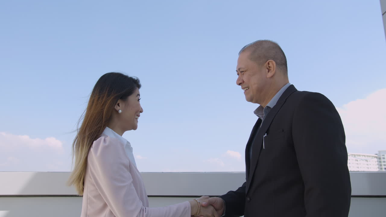 Businessman and Businesswoman Shaking Hands In A Building Rooftop