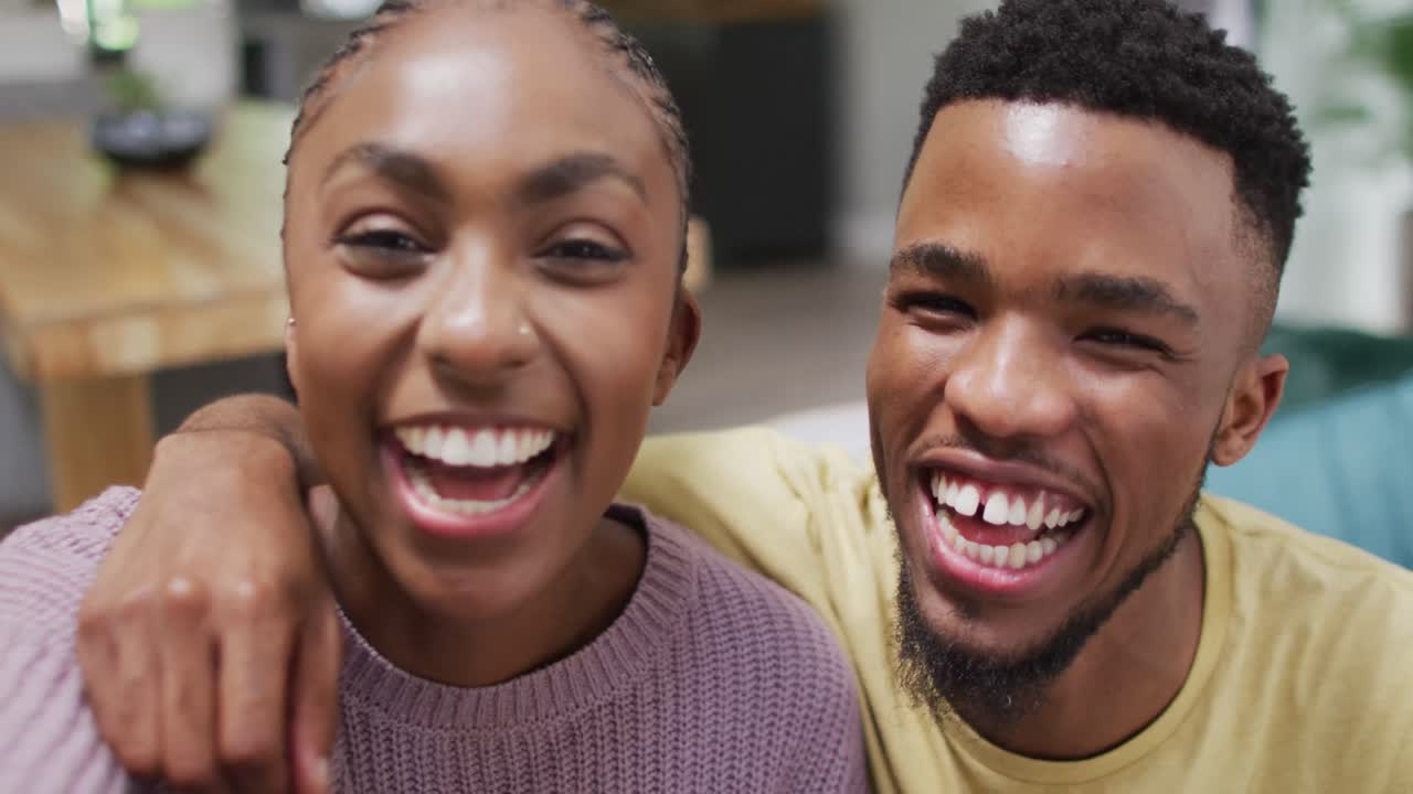 Heureux couple afro-américain parlant à la caméra pendant un appel vidéo.