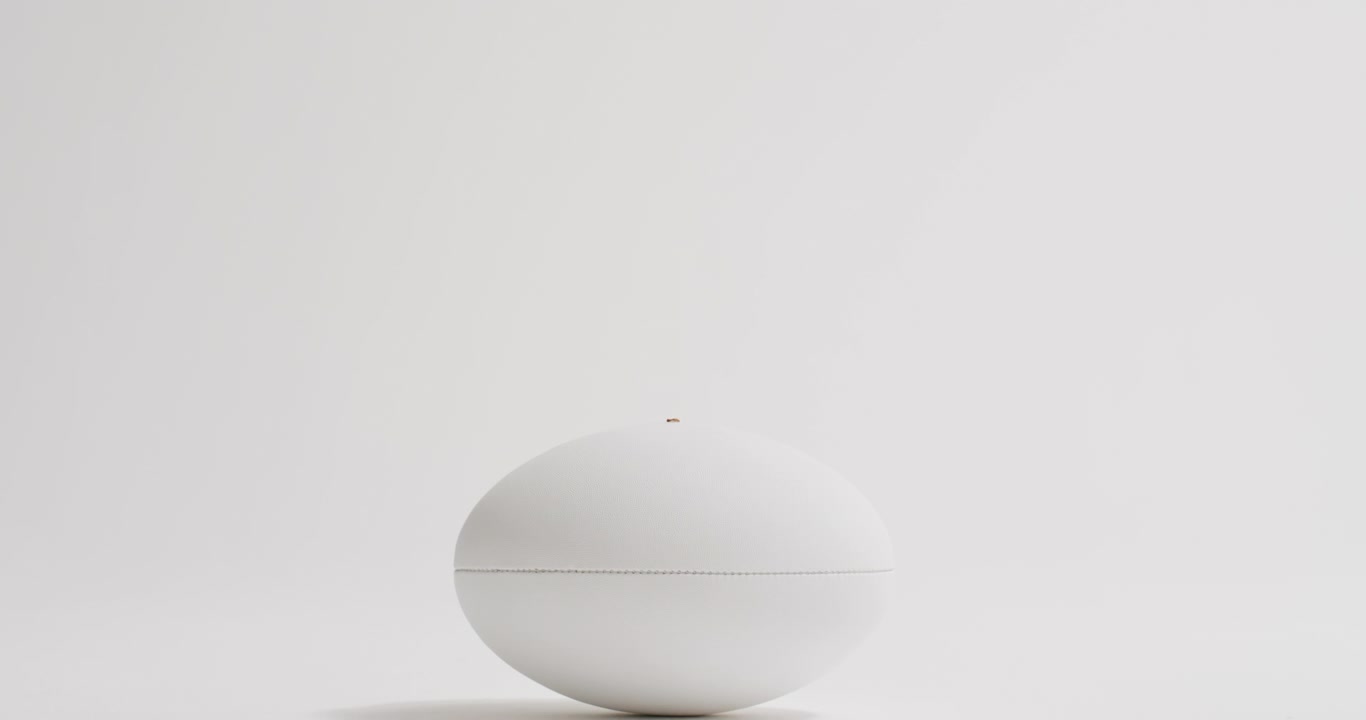 Ballon de rugby blanc sur fond blanc avec espace pour texte, au ralenti