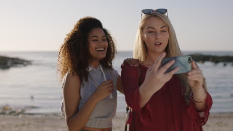 girlfriends posing for selfie photo using smartphone on sunny beach smiling laughing together