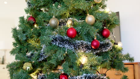 decorating christmas tree with red and gold ornaments at home, feeling festive