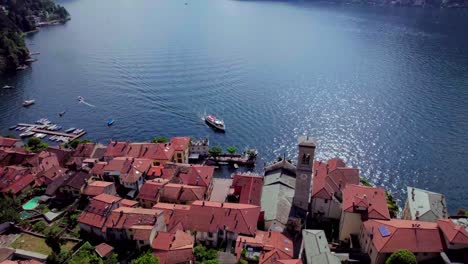 boat docking at torno village on lake como, aerial backward reveal, italy