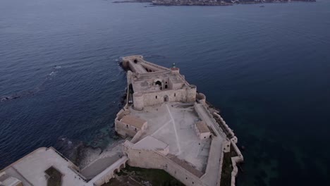 Órbita-Aérea-Castillo-Medieval-Maniace-Al-Atardecer,-Siracusa,-Sicilia