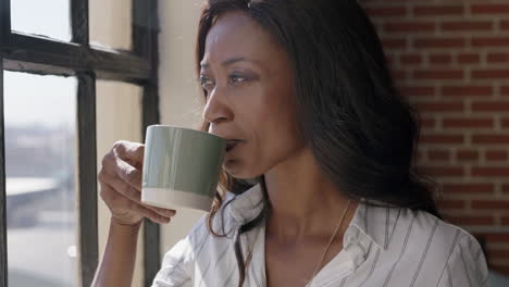 retrato de una mujer afroamericana feliz usando un teléfono inteligente bebiendo café en casa navegando por los mensajes de las redes sociales disfrutando de una mañana relajada mirando por la ventana enviando mensajes de texto en el teléfono móvil