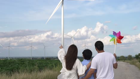 concepto de familia feliz progresiva en un parque eólico con vehículo eléctrico.