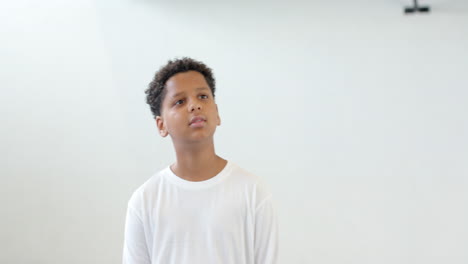 in school, boy looking thoughtful in school gym, wearing white shirt, copy space