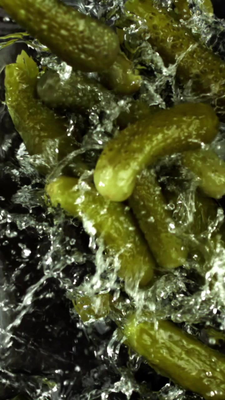 Cornichons frais éclaboussant dans l'eau au ralenti