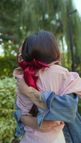 dos mujeres abrazadas en un parque.