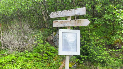 fotografía panorámica de un cartel que muestra el camino a una cueva en noruega durante el verano