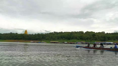 asian tourist riding on the local boat for sightseeing at sangklaburi, kanchanaburi, thailand