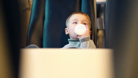 boy in the train drinking milk from bottle