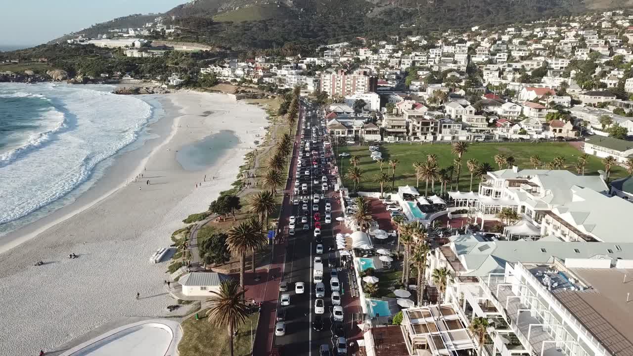 flying over the streat victoria road with the hotels left and the beach left tilting up to lions head mountain over the city camps bay