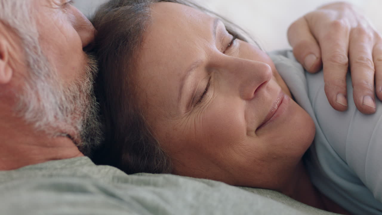 pareja feliz madura acostada en la cama abrazándose compartiendo una relación romántica disfrutando de la intimidad juntos en casa
