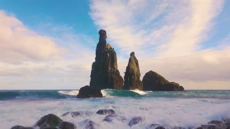 slow motion shot of crashing waves on rocky beach in front of rock formation on madeira island