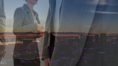 sección media de los hombres de negocios estrechando las manos contra la vista aérea del paisaje urbano por la noche