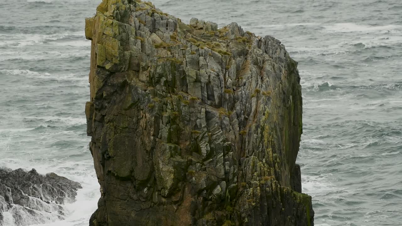 Giant natural rock stack with the ocean breaking against the cliff face in the background, along the coastline of Lewis Island in the Outer Hebrides of Scotland
