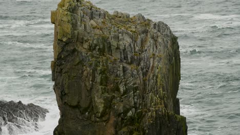 giant natural rock stack with the ocean breaking against the cliff face in the background, along the coastline of lewis island in the outer hebrides of scotland