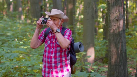 Älterer-Großvater-Auf-Wandertour-Erkundet-Die-Tierwelt-Und-Fotografiert-Im-Wald-Mit-Retro-Kamera