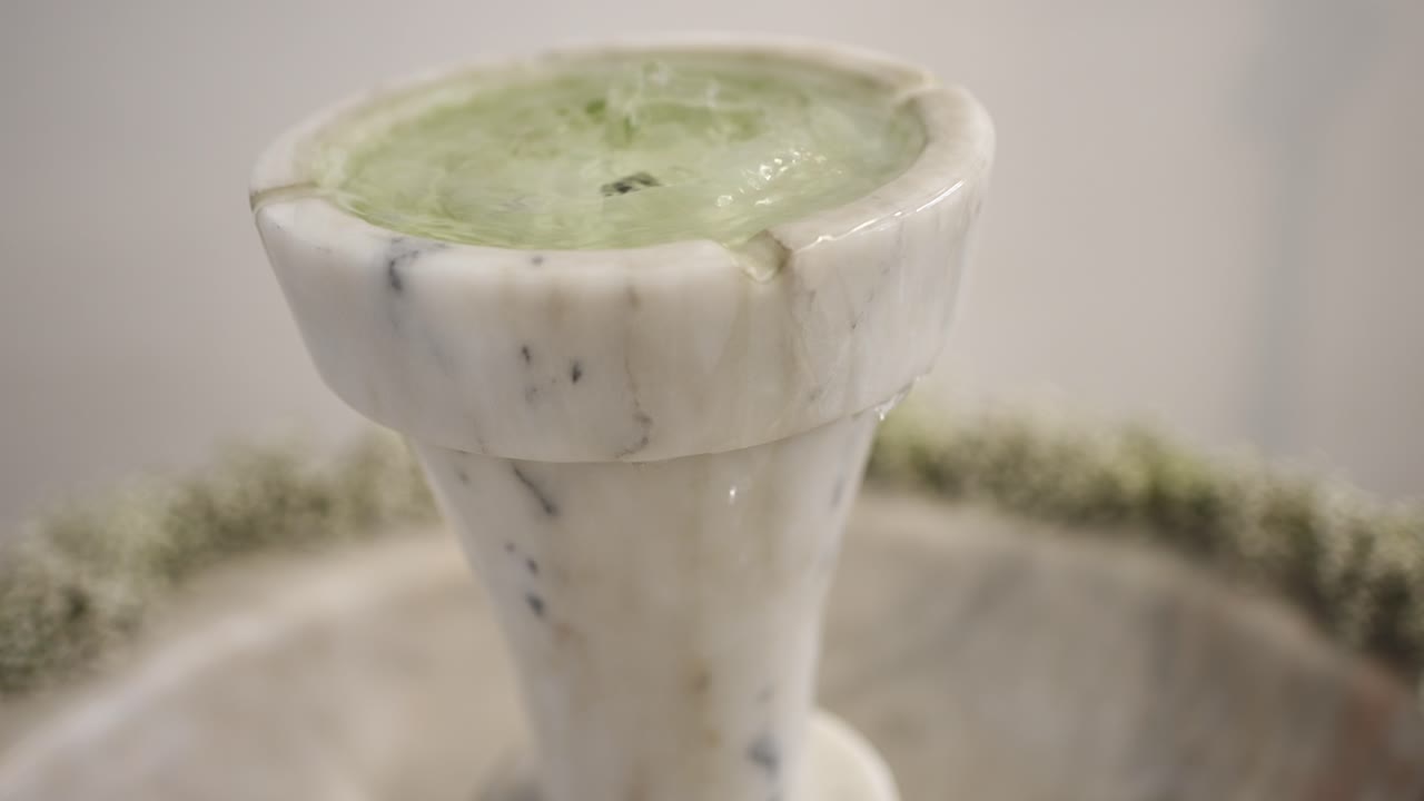 primer plano de una pila de agua bendita de mármol con suaves ondas y flujo