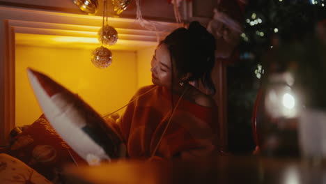 una mujer se relaja en una iluminación acogedora, escuchando música, rodeada de decoración navideña