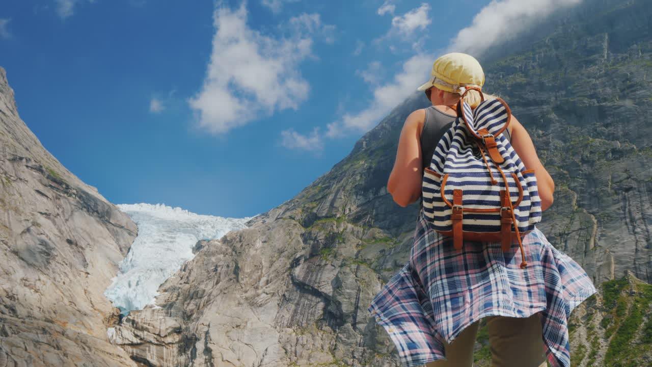una mujer activa y exitosa se para en una roca mira las montañas y el glaciar en la cima