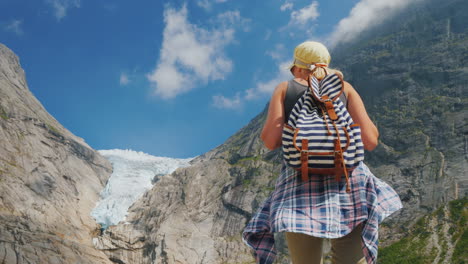 An-Active-Successful-Woman-Stands-On-A-Rock-Looks-At-The-Mountains-And-The-Glacier-On-Top