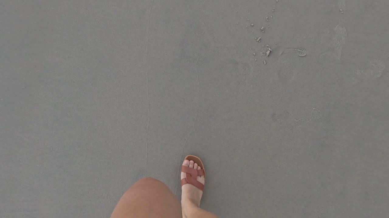 모래 해변 을 따라 맨발 로 산책 하는 사람