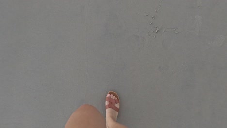 person strolling along a sandy beach barefoot