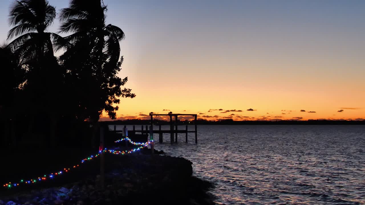 agua ondulante al atardecer cerca del muelle con una cadena de luces
