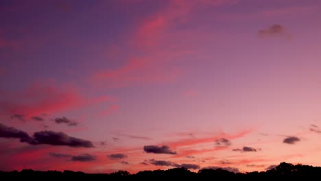 Nubes-Oscuras-Que-Se-Mueven-Lentamente-En-Un-Cielo-Rosado-Y-Morado-Al-Atardecer-4k