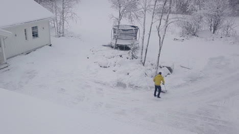 Schneeschaufelnder-Mann-Auf-Privatgrundstück-Im-Winter,-Luftaufnahme