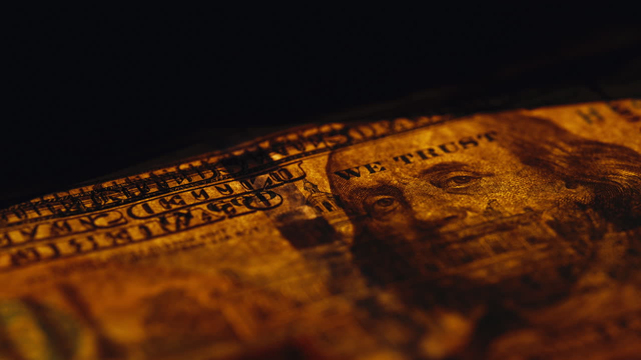 Reverse side hundred note shown beneath glowing desk light indoors macro shot