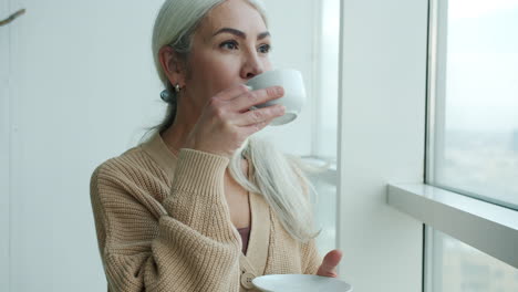 senior woman enjoying a drink by the window