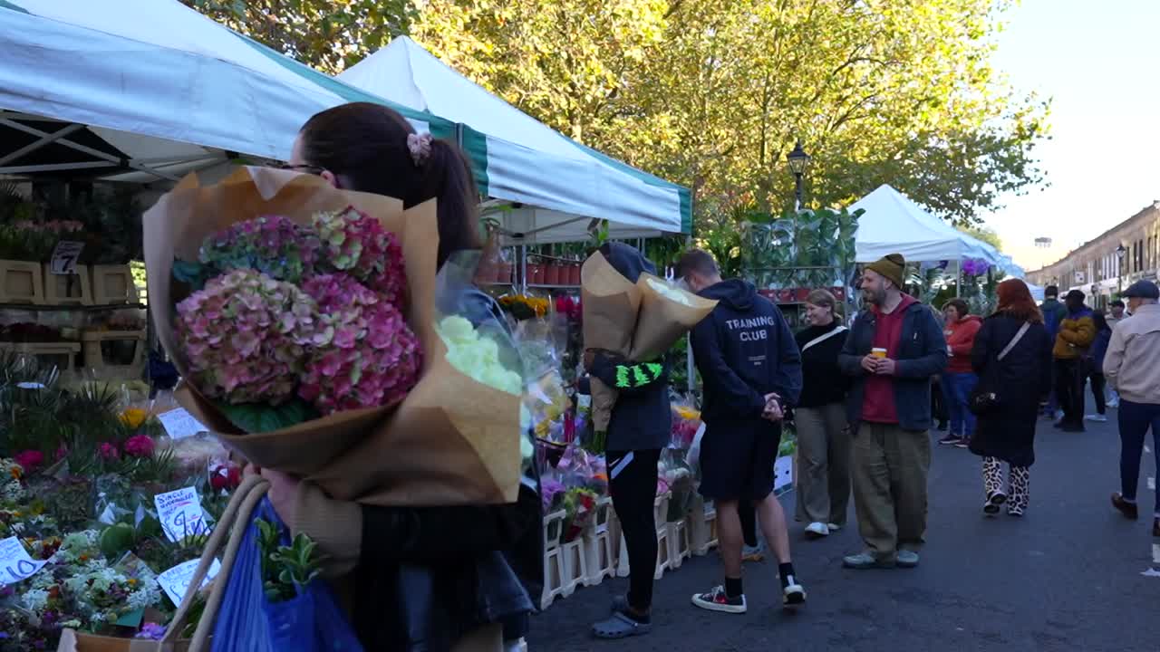 People buying flowers at Columbia Road Flower Market in Bethnal Green, London, UK. Wide shot