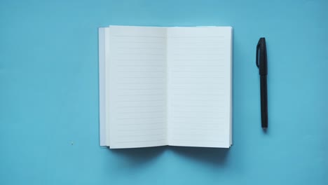 open notebook and pen on blue background