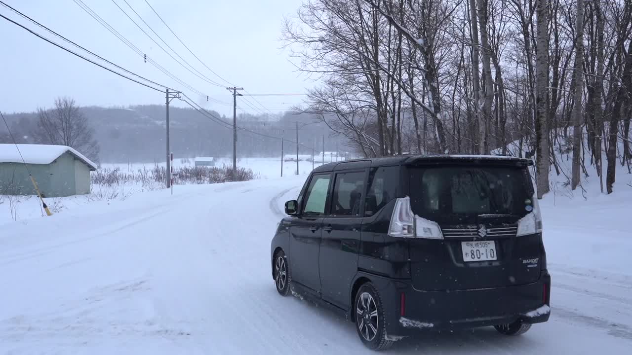 A black van drives through heavy snowfall
