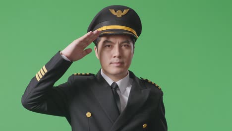 close up of asian man pilot is respectful, saluting while standing in the green screen background studio