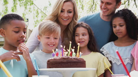 Padres-Con-Hijo-Celebrando-Cumpleaños-Con-Amigos-Haciendo-Fiesta-En-El-Jardín-Y-Apagando-Velas