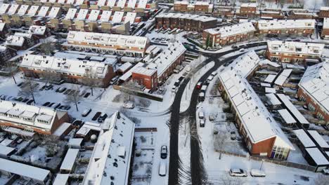 drone siguiendo un coche rojo conduciendo a través de un hermoso barrio suburbano cubierto de nieve