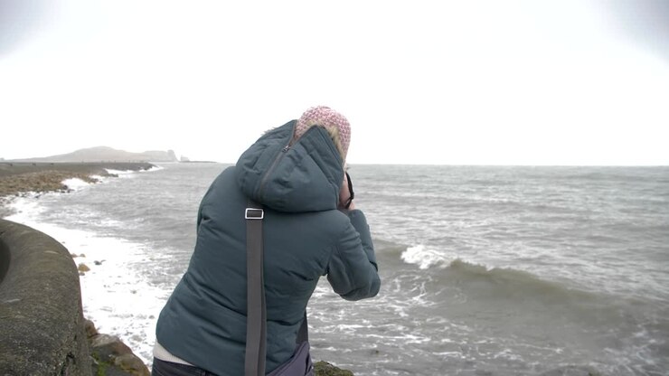 Female photographer taking photos of rough sea