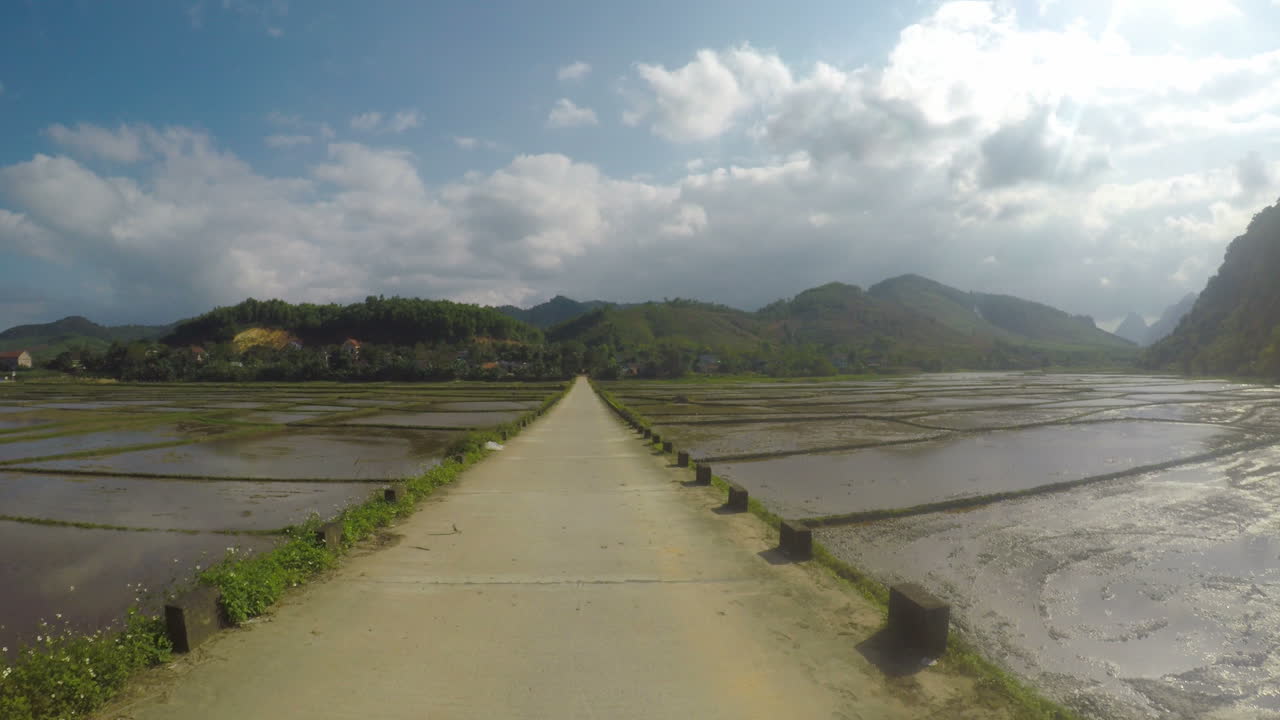 푸른 하늘을 배경으로 쌀 패티 사이의 베트남 콘크리트 도로, gopro 4k