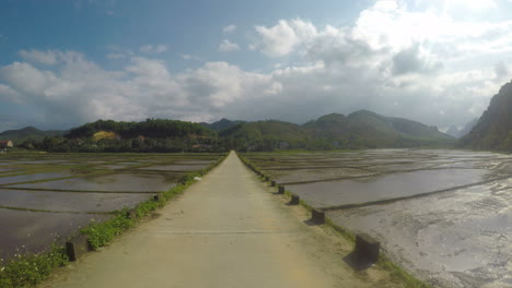 Vietnam-concrete-road-between-rice-patties-against-the-blue-sky,-gopro-4k