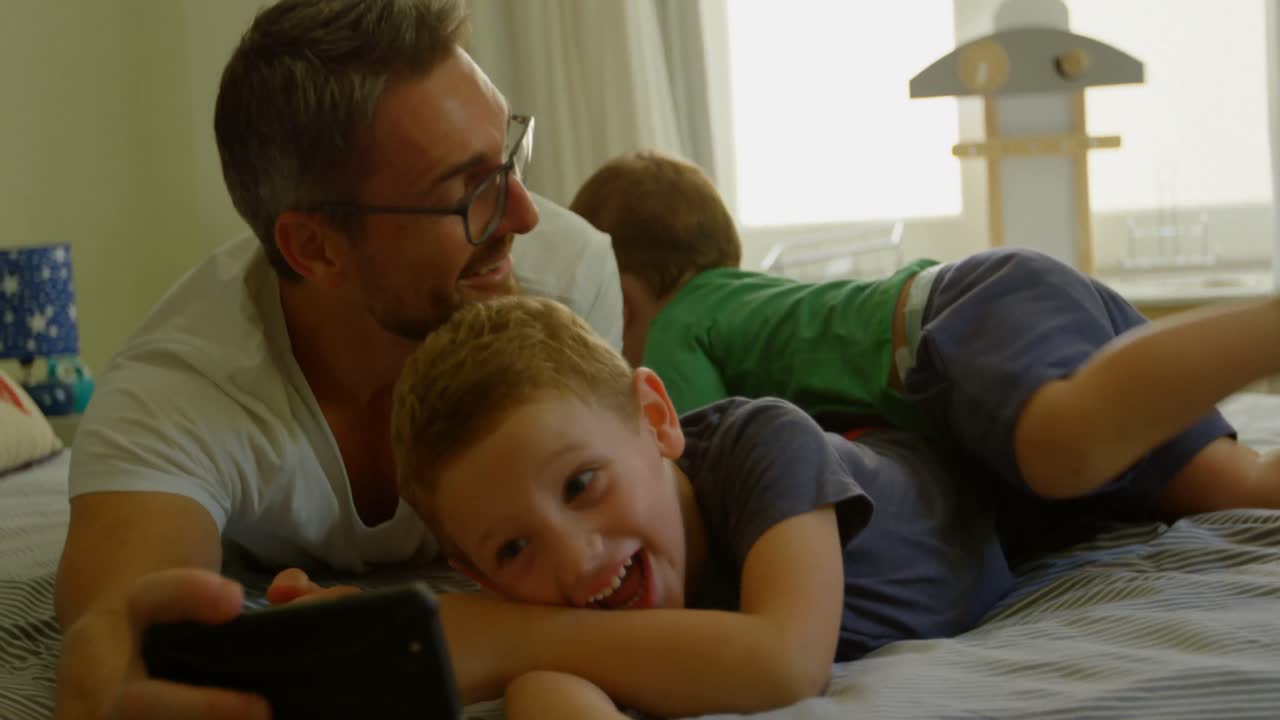 padre y hijos tomando selfies en la cama 4k
