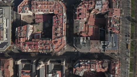 Top-down-shot-of-houses-arranged-into-blocks-surrounded-by-streets.-Urban-borough-from-above.-Barcelona,-Spain