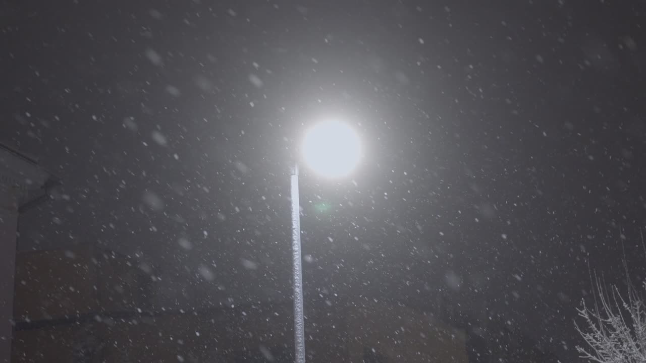 Gatelykt med snø som faller rundt om natten i byen