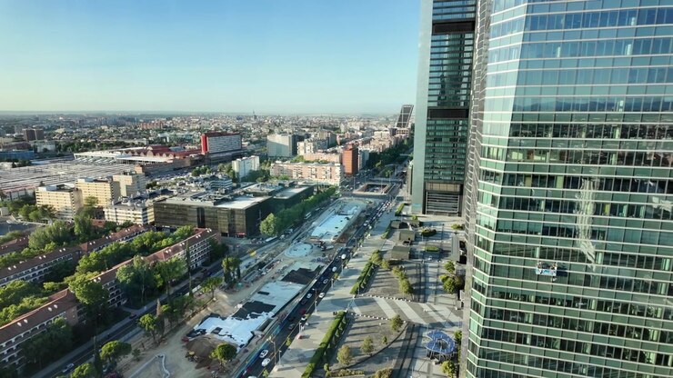 Veduta dall'alto da un grattacielo di Madrid sulle Cuatro Torres, strade cittadine, traffico ed edifici urbani circostanti.